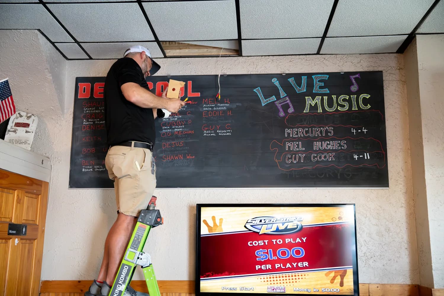 A Reliant technician on a ladder installing a low-voltage device in a commercial space.