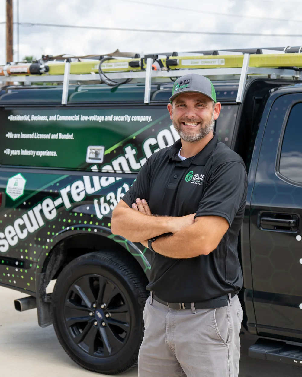 A Reliant Security technician standing in front of a branded Reliant service truck.
